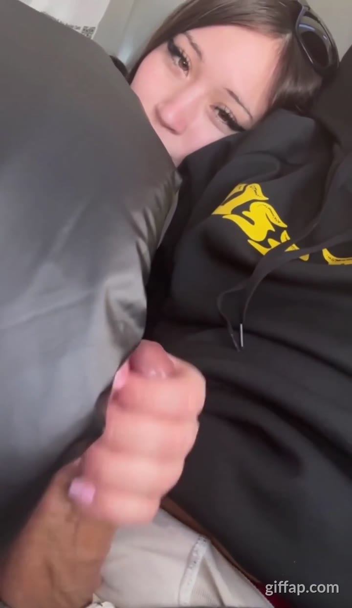 The girl is giving her boyfriend a handjob on the plane.